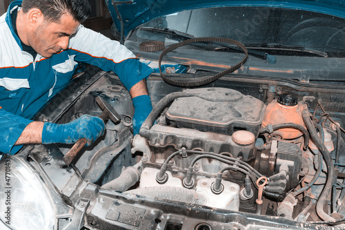 Auto mechanic working on car engine in mechanics garage - Repair service. authentic close-up shot photo