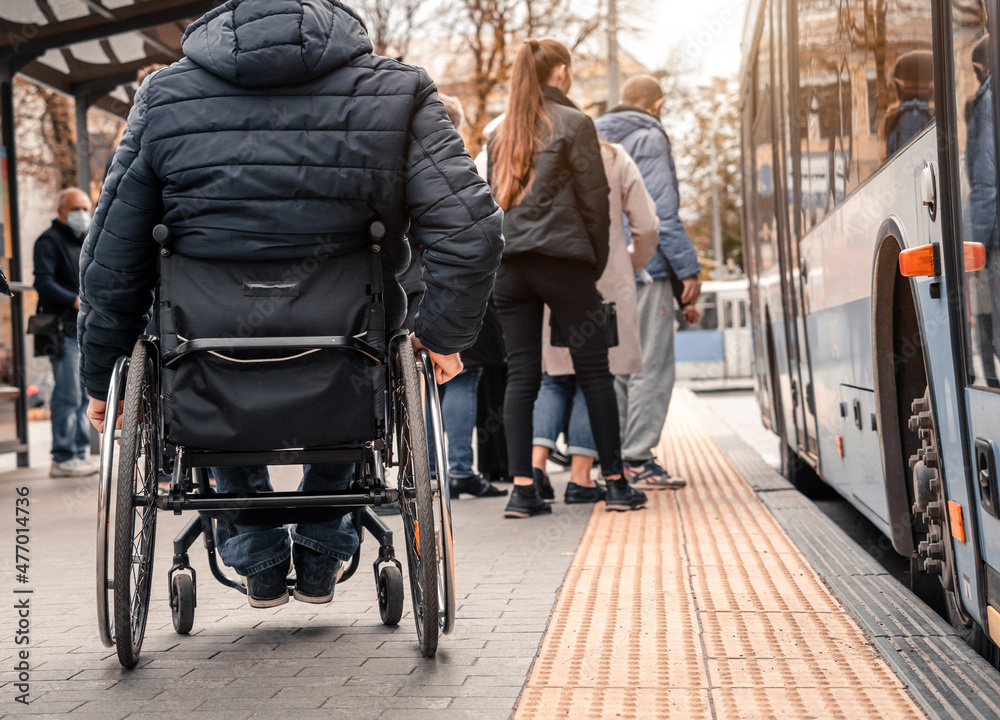 Obraz premium Person with a physical disability waiting for city transport with an accessible ramp.