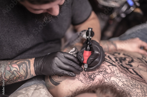 Tattooer makes tattoo in salon