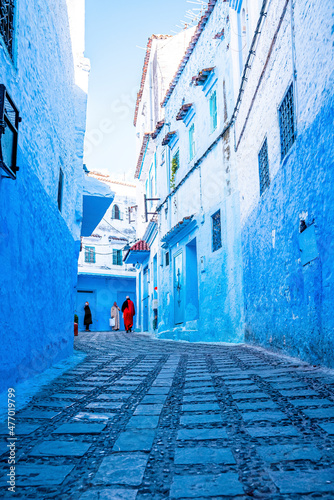 Chefchaouen, Morocco. October 10, 2021. Pedestrians walking on narrow street between traditional residential buildings © Aerial Film Studio