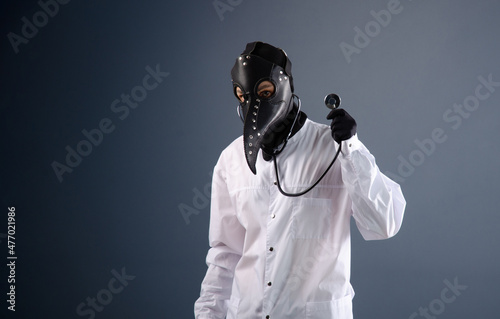 Obraz na plátně a doctor in a dressing gown wearing a plague doctor mask with a stethoscope in h