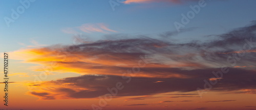 Real sunset sky with gentle colorful clouds without birds. Natural background.