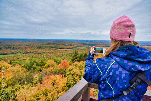Woman photographing fall tree colors in the midwest
