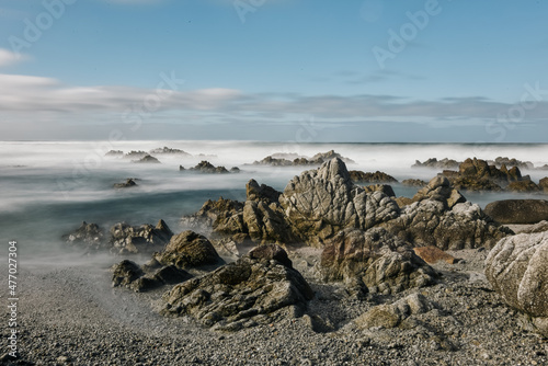 Long camera exposure of Pacific Ocean waves on rocky coastline of California photo