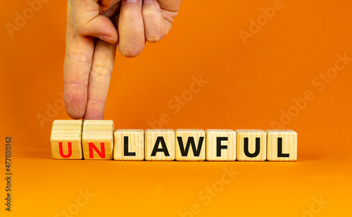 Lawful or unlawful symbol. Businessman turns wooden cubes and changes the word unlawful to lawful. Beautiful orange table, orange background, copy space. Business and lawful or unlawful concept. photo