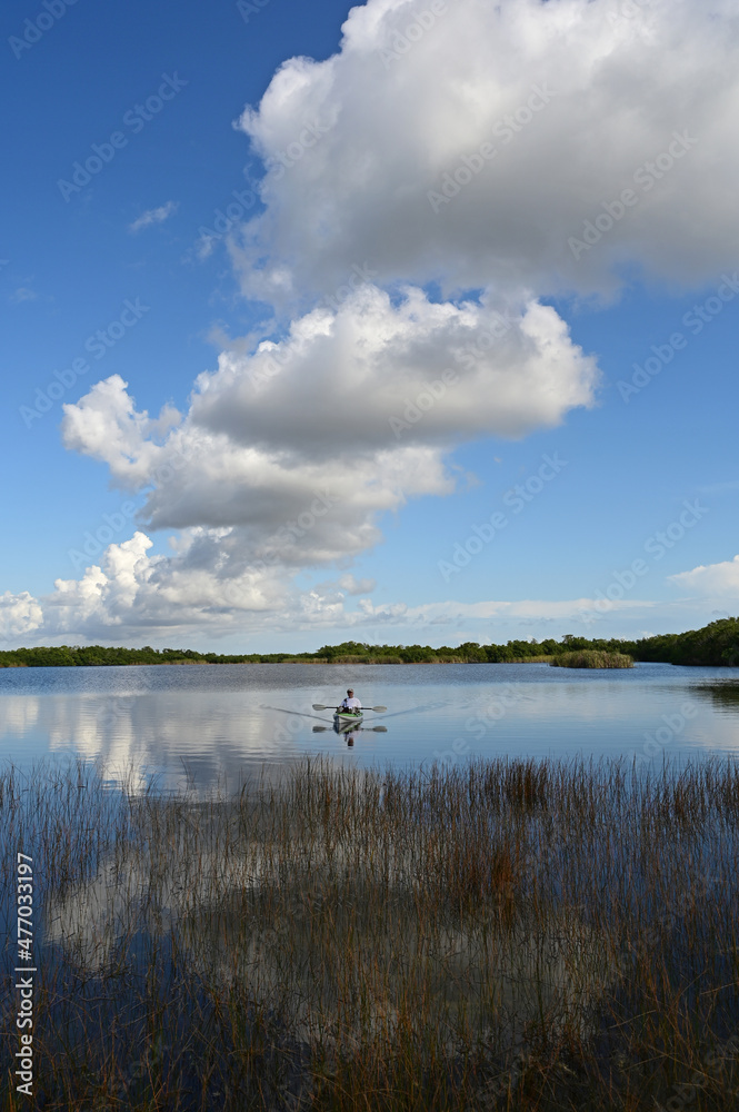 Active senior kayaking on calm waters of Nine Mile Pond in Everglades National Park, Florida on sunny afternoon under beautiful winter cloudscape. Active senior kayaking on calm waters of Nine Mile Pond in Everglades National Park, Florida on sunny afternoon under beautiful winter cloudscape.