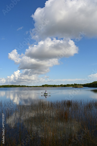 Active senior kayaking on calm waters of Nine Mile Pond in Everglades National Park, Florida on sunny afternoon under beautiful winter cloudscape.