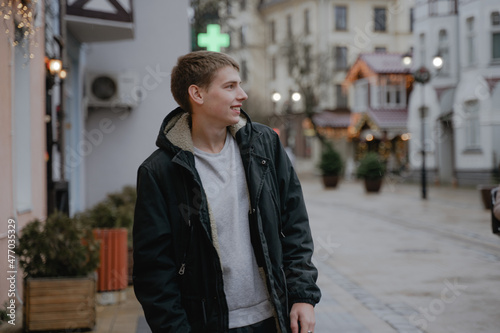 portrait of a smiling teenager in profile, in a black winter jacket on the city streets