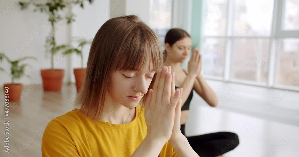 Relaxed young women in sportswear is meditating in lotus position, yoga class Relaxed young women in sportswear is meditating in lotus position, yoga class