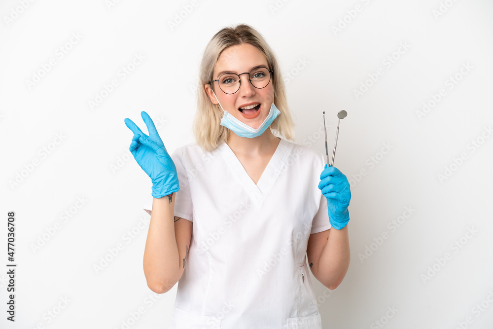 Dentist caucasian woman holding tools isolated on white background smiling and showing victory sign Dentist caucasian woman holding tools isolated on white background smiling and showing victory sign
