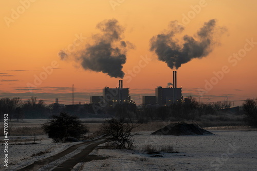Die Schornsteine des Müllheizkraftwerks Magdeburg qualmen, während die untergehende Sonne den Himmel verfärbt.