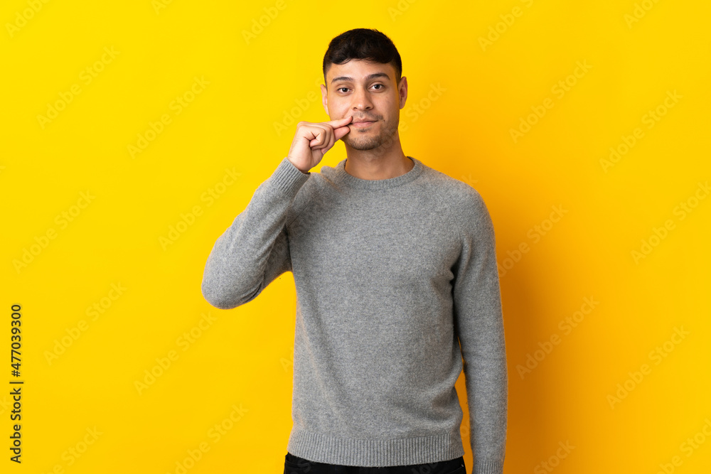 Young Colombian man isolated on yellow background showing a sign of silence gesture Young Colombian man isolated on yellow background showing a sign of silence gesture