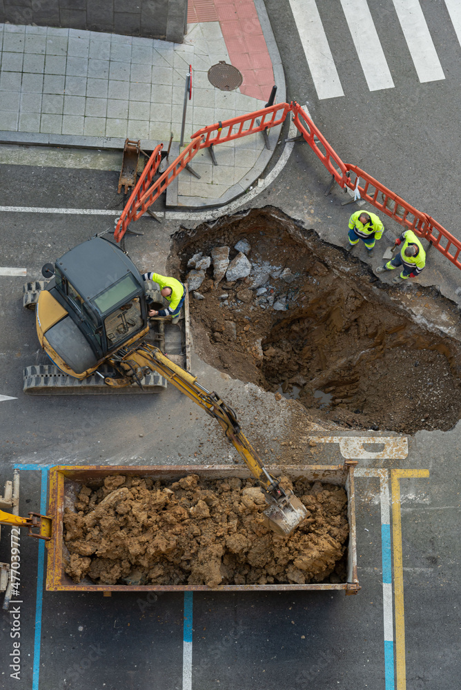 cavando un agujero en el suelo para reparar la canalización de agua o obras y canalización de agua en una calle con una  mini excavadora 