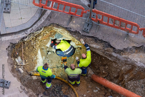 revisando un agujero en la carretera para reparar las tuberías de una ciudad o colocando canalizaciones de agua o alcantarillado photo