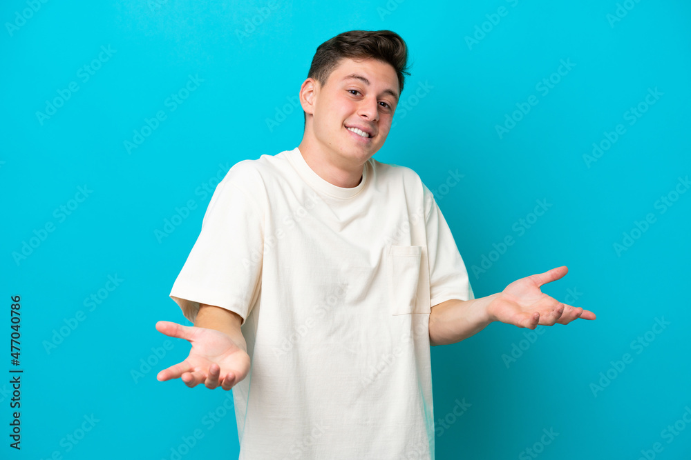 Young handsome Brazilian man isolated on blue background happy and smiling