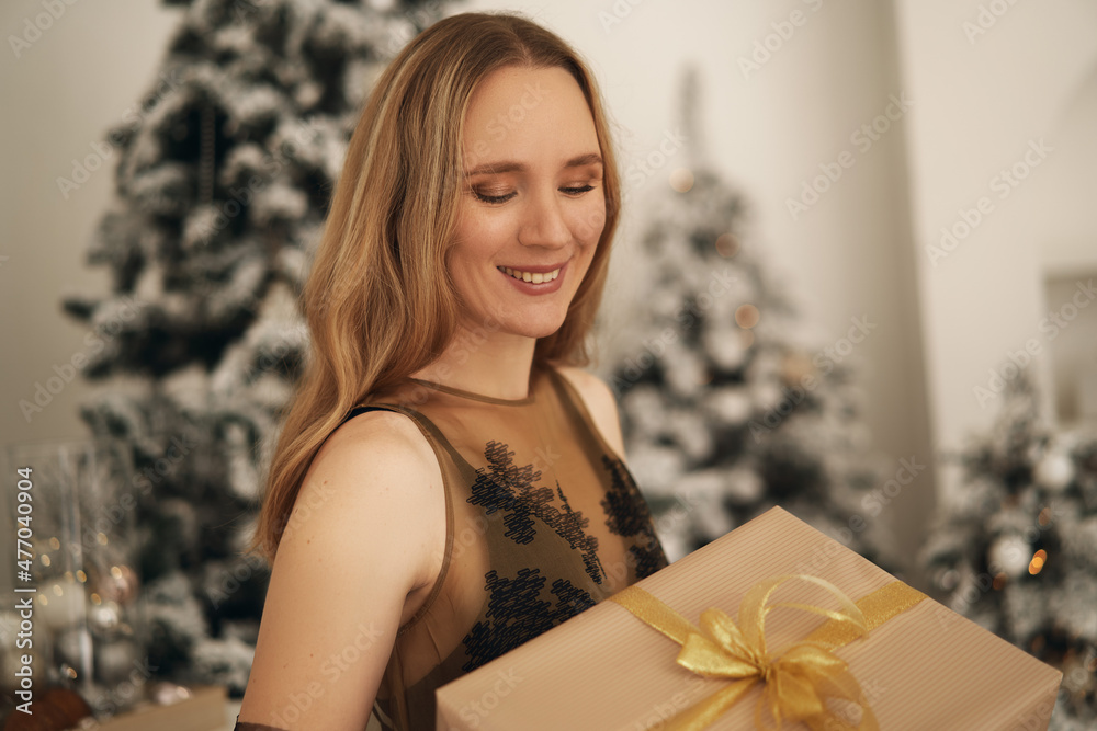 girl in a black dress by the fireplace with a gift in her hands girl in a black dress by the fireplace with a gift in her hands