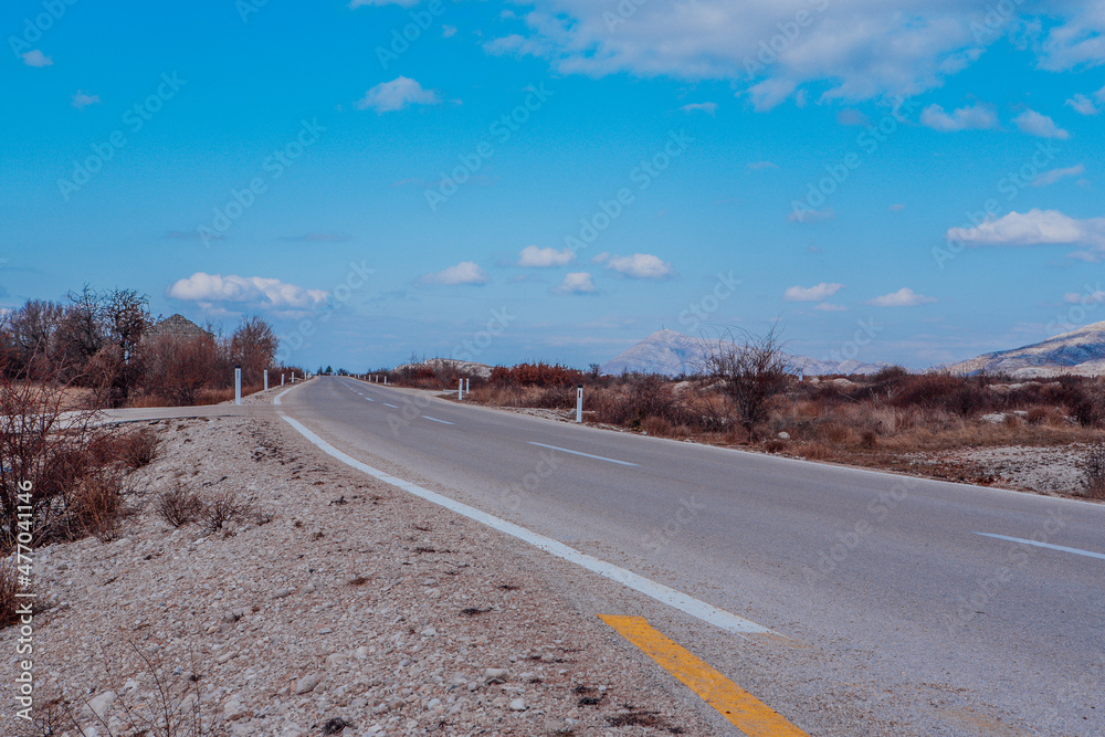 Asphalt road goes to the horizon. Landscape view perspective of road with white clouds on blue sky. Traveling by car. Trendy background for branding, calendar, multicolor card, banner, cover, header