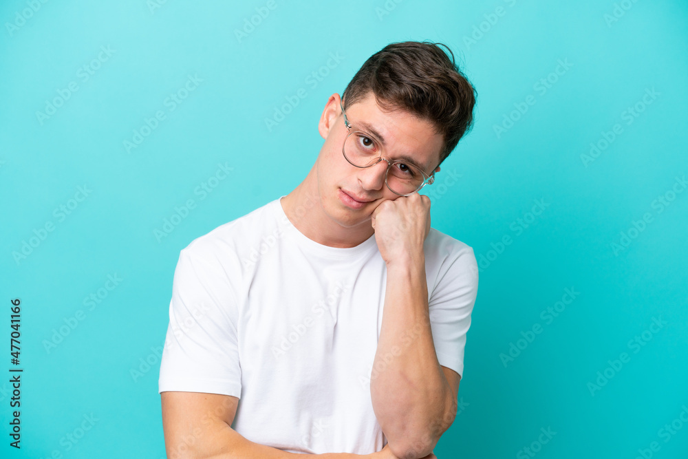 Young handsome Brazilian man isolated on blue background With glasses and with sad expression Young handsome Brazilian man isolated on blue background With glasses and with sad expression