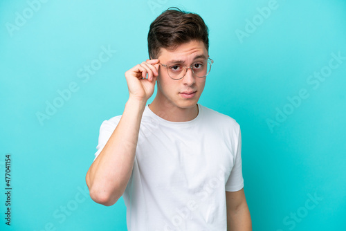 Young handsome Brazilian man isolated on blue background With glasses and frustrated expression