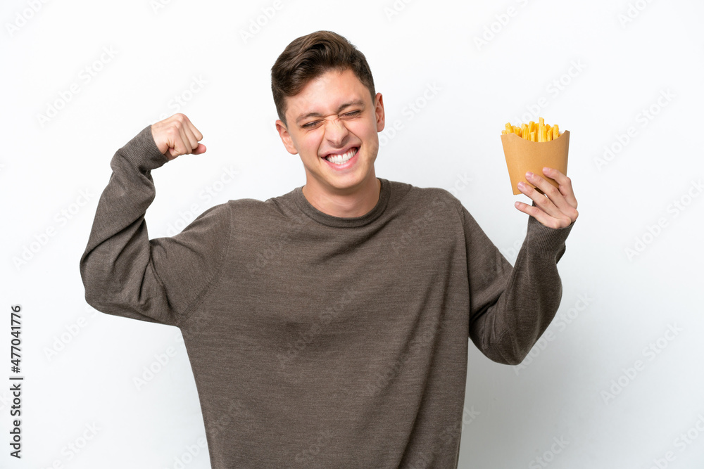 Young Brazilian man holding fried chips isolated on white background doing strong gesture Young Brazilian man holding fried chips isolated on white background doing strong gesture