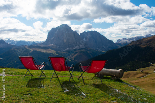 Red lawn chairs with dramtic Mountain background. Dolomites in European Alps. Gardena Pass, Italy. Vacation Theme photo