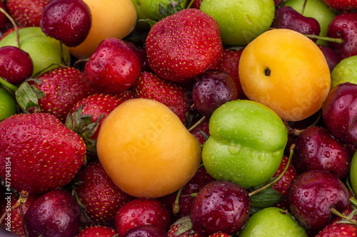 Ripe strawberry  apricot  cherry  green plum with water drops. Fresh Summer fruit background close up image.