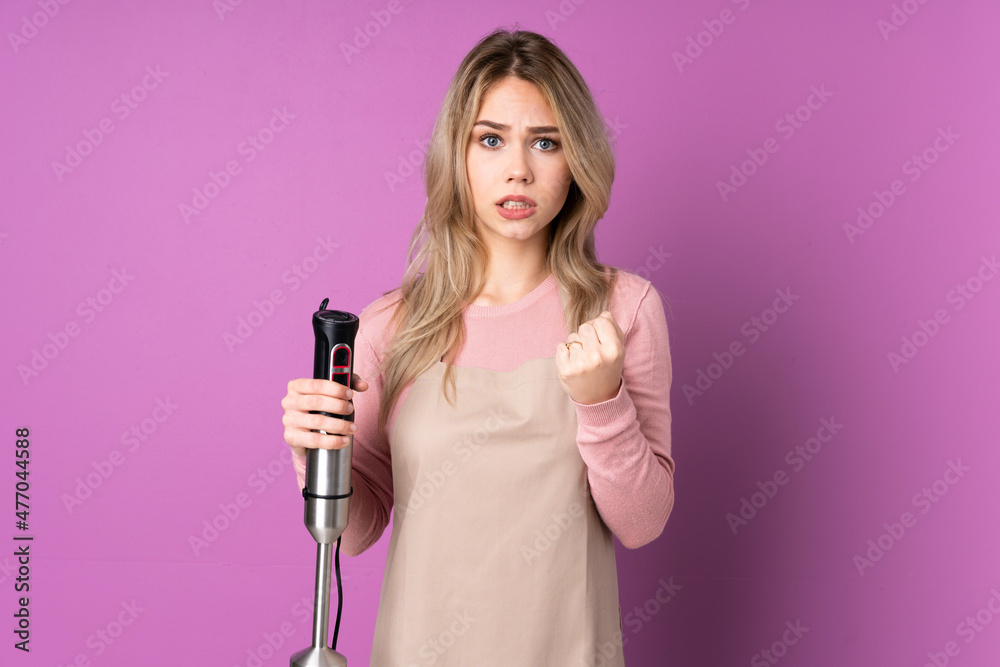 Teenager Russian girl using hand blender isolated on purple background frustrated by a bad situation Teenager Russian girl using hand blender isolated on purple background frustrated by a bad situation