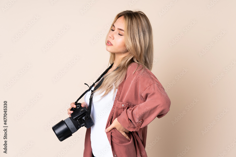 Young photographer girl over isolated background suffering from backache for having made an effort Young photographer girl over isolated background suffering from backache for having made an effort