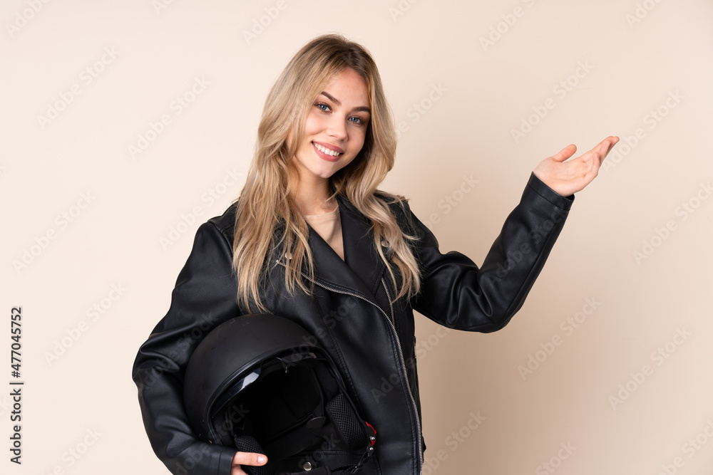 Russian girl with a motorcycle helmet isolated on beige background extending hands to the side for inviting to come