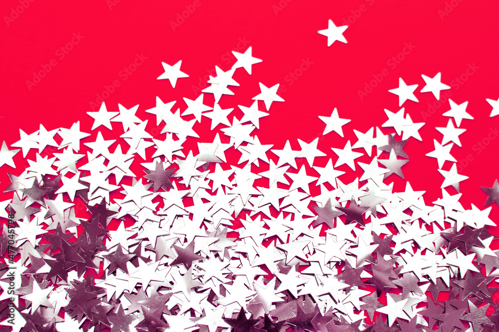 Background of shiny silver little stars on red background. Christmas concept. Glitter texture.