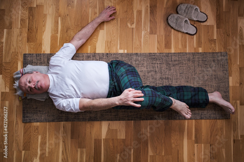 Senior caucasian man doing yoga Spine twisting pose photo