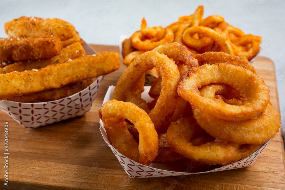 Ταπετσαρία A view of a variety of deep fried appetizers, featuring onion rings, zucchini, and curly fries