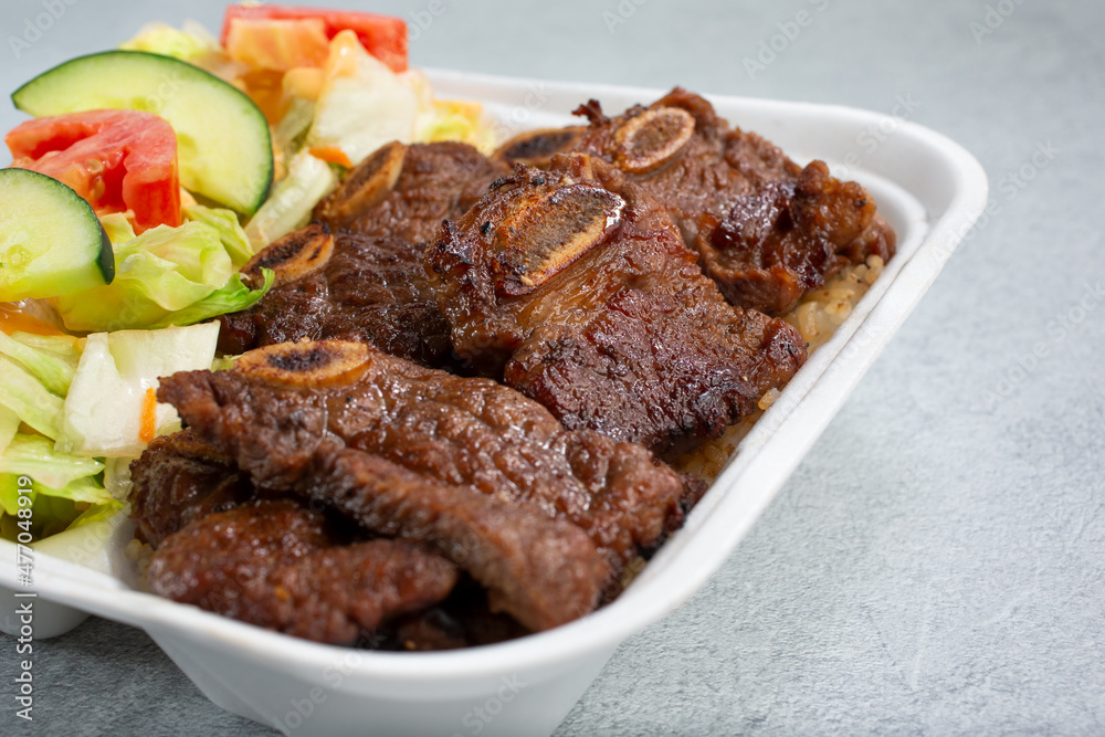 A view of a bento box, featuring Hawaiian style beef short ribs. A view of a bento box, featuring Hawaiian style beef short ribs.