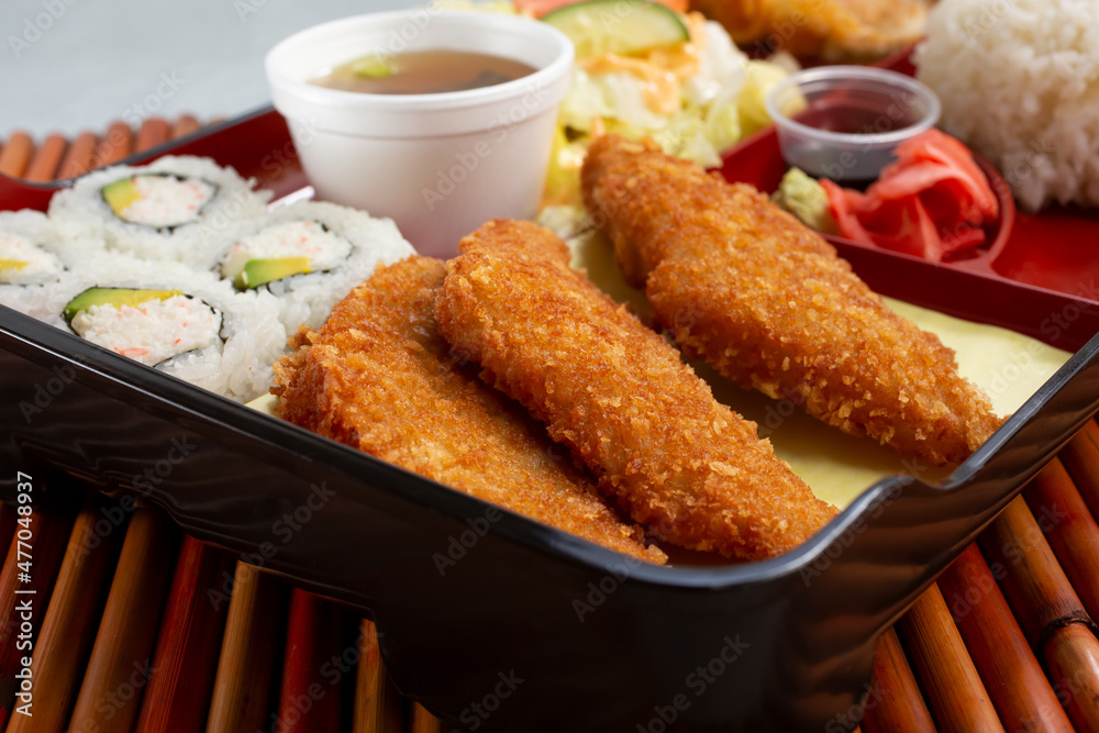 A closeup view of a bento box, featuring California rolls and potato cakes. A closeup view of a bento box, featuring California rolls and potato cakes.