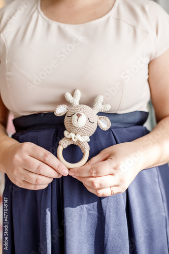 In the hands of a knitted toy for decorating a Christmas tree.