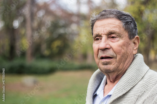 Old man relaxing outdoors and looking away. Portrait of senior man looking thoughtful