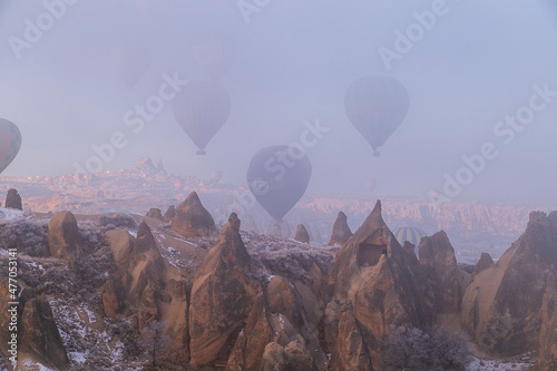 Hot air balloons flying over spectacular Cappadocia. Beautiful view of hot air balloons floating in sunrise blue sky over the mountain landscape of fairy chimneys