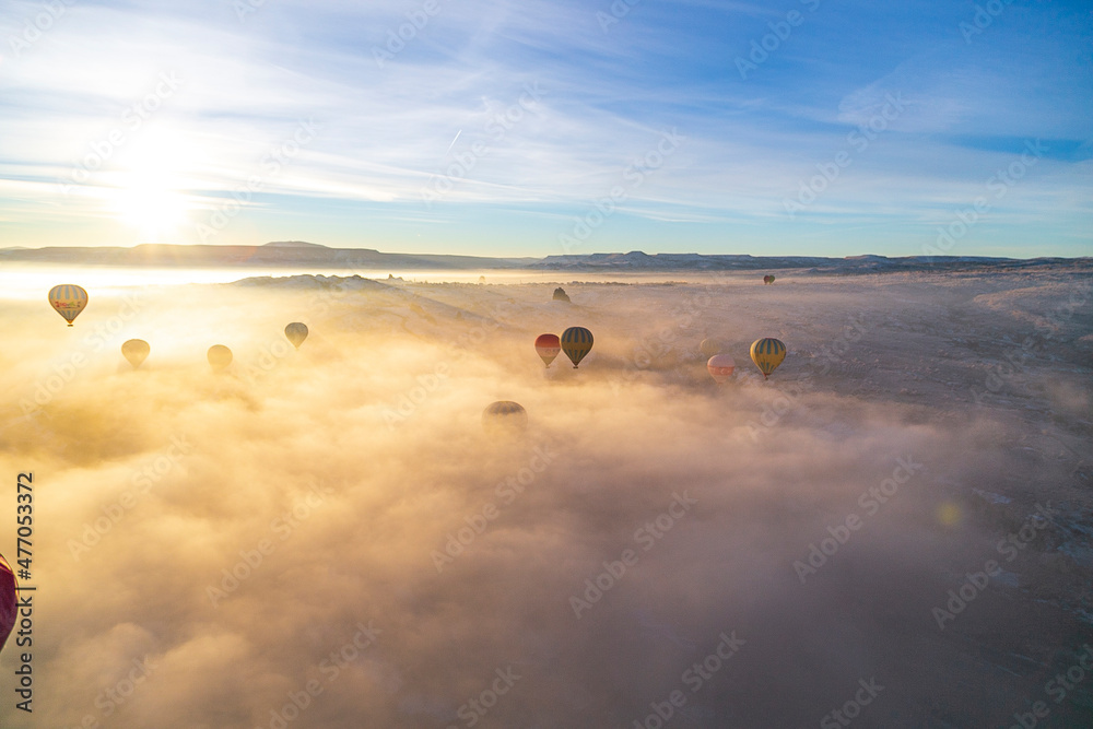 Hot air balloons flying over spectacular Cappadocia. Beautiful view of hot air balloons floating in sunrise blue sky over the mountain landscape of fairy chimneys Hot air balloons flying over spectacular Cappadocia. Beautiful view of hot air balloons floating in sunrise blue sky over the mountain landscape of fairy chimneys