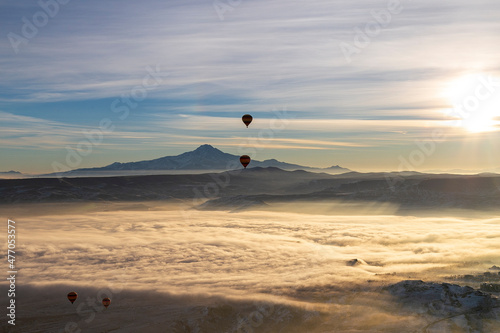 Hot air balloons flying over spectacular Cappadocia. Beautiful view of hot air balloons floating in sunrise blue sky over the mountain landscape of fairy chimneys