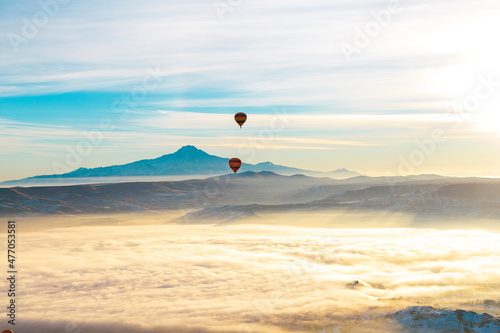 Hot air balloons flying over spectacular Cappadocia. Beautiful view of hot air balloons floating in sunrise blue sky over the mountain landscape of fairy chimneys