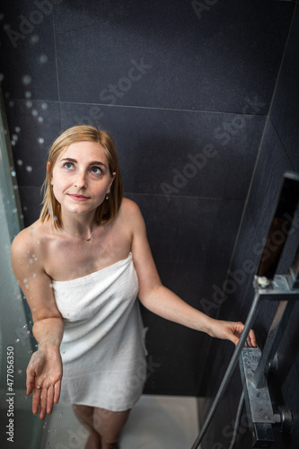 Pretty  young woman taking a long hot shower washing her hair in a modern design bathroom