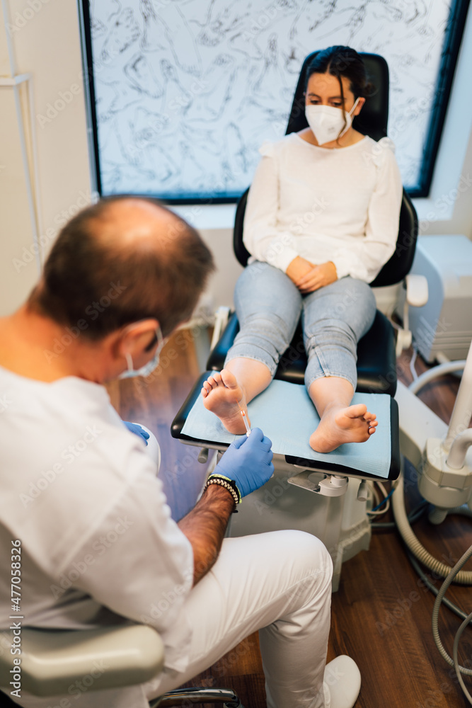 Obraz premium Chiropodist exploring a patient with diabetic foot in the medical center with face mask during COVID coronavirus pandemic.