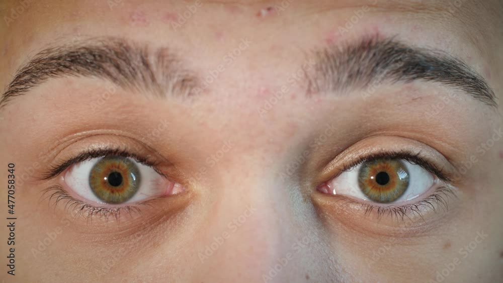 Close up of shocked and surprised male face with hazel eyes raising eyebrows. Young male model with natural central heterochromia and blue brown eye colors looking at camera. Slow-motion, 4K. Close up of shocked and surprised male face with hazel eyes raising eyebrows. Young male model with natural central heterochromia and blue brown eye colors looking at camera. Slow-motion, 4K.
