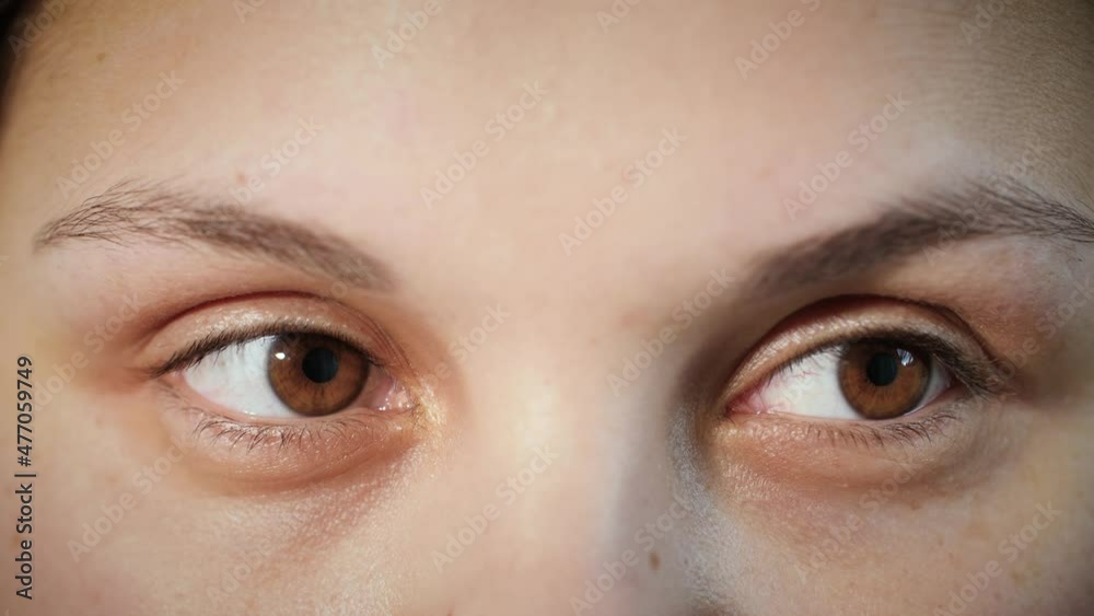 Close up of face of young Arab woman. Girl looking around with brown eyes. Macro portrait of female middle eastern Muslim model with smooth skin moving her eyes from one side to another. 4K.