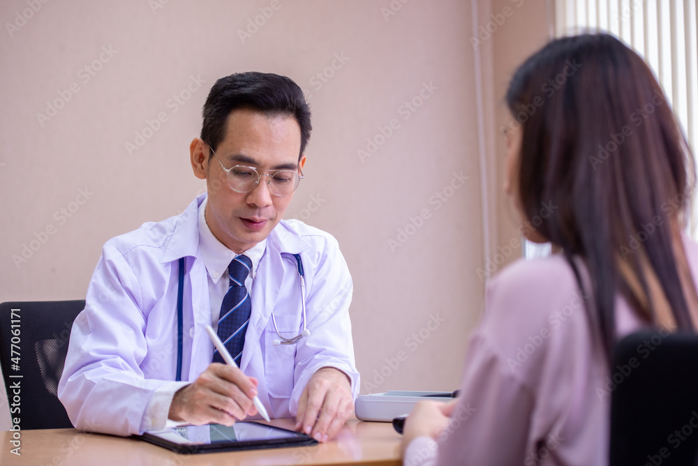 Doctor asking patient history, using a tablet to take notes, Asian woman. Doctor asking patient history, using a tablet to take notes, Asian woman.
