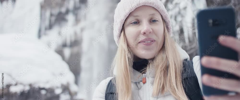 Woman takes selfie photo hiking at winter Alps waterfall in close up Woman takes selfie photo hiking at winter Alps waterfall in close up
