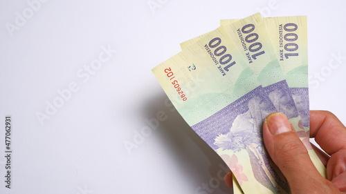 A man's hand is making a payment. Male hand showing Indonesian rupiah note. Indonesian Rupiah the official currency of Indonesia. Business and finance concept. Uang 1000 Rupiah.
