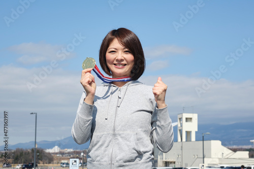 メダルを手に持つ優勝した女性　日本人　女性