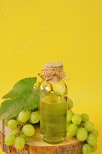 Grape seed oil.Base cosmetic oil for massage and care for face and body. bottle and bunch of grapes on a bright yellow background.Organic Natural Bio Grape Seed Oil.natural cosmetics