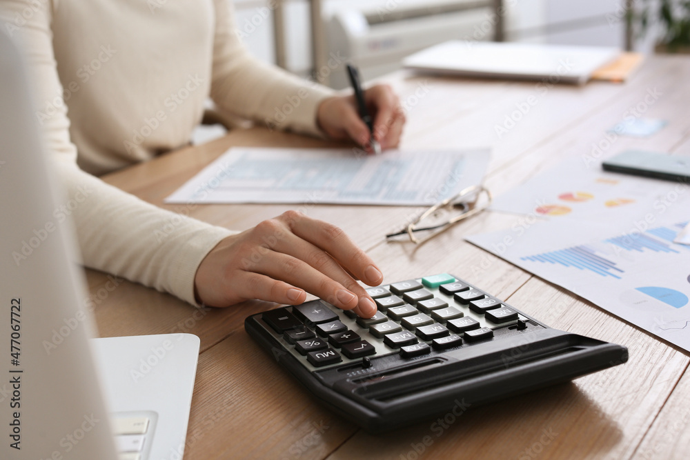Tax accountant with calculator working at wooden table, closeup